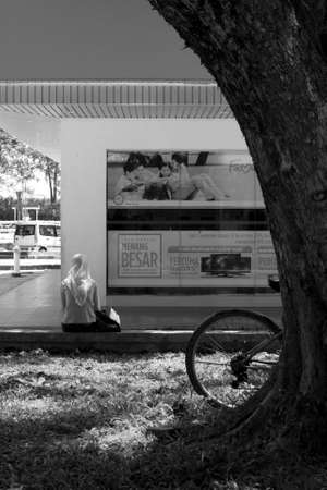 SABAH, EAST MALAYSIA OCTOBER 1 2009: A Muslim woman in the small town of Kudat at the Tip of Borneo sits outside the entrance to a commercial bank in East Malaysia. のeditorial素材