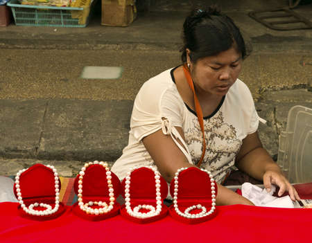 PHUKET, THAILAND SEPTEMBER 30 2011: A female street vendor sells pearl necklaces at the Downtown Market in Phuket Town during the annual Vegetarian Festival. のeditorial素材