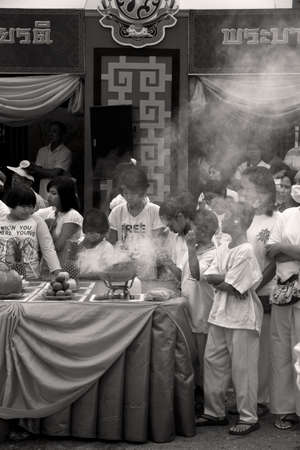 PHUKET, THAILAND - OCTOBER 1 2011: Spectators dressed in ceremonial white in Phuket Town gather around a worship station burning incense during the annual Phuket Vegetarian Festival.のeditorial素材