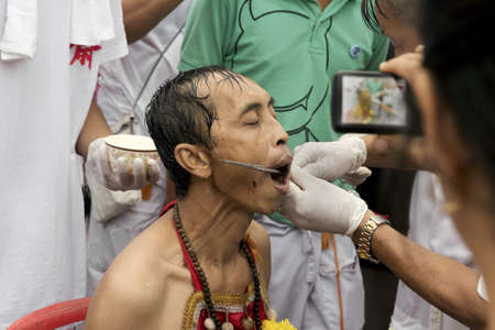 PHUKET, THAILAND - OCTOBER 3 2011: A Ma Song endures the pain of a skewer extraction at the Jui Tui Chinese Shrine in Phuket Town during the annual Phuket Vegetarian Festival.のeditorial素材
