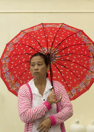PHUKET, THAILAND - OCTOBER 3 2011: A devotee attending the annual Phuket Vegetarian Festival stands under her umbrella during a rain storm at the Jui Tui Chinese Shrine.のeditorial素材