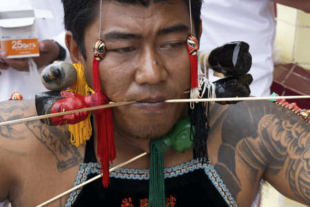 PHUKET, THAILAND - OCTOBER 5 2011: A ma song (vessel of the gods) has his cheeks pierced in a ritual ceremony at the Sui Boon Tong Chinese Shrine during the annual Phuket Vegetarian Festival. のeditorial素材