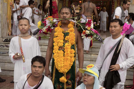 PHUKET, THAILAND - OCTOBER 3 2011: A Mah Song (spirit medium) with entourage of attendants  waits to have his piercings extracted at the JuiTui Shrine in Phuket Town during the annual Phuket Vegetarian Festival.のeditorial素材