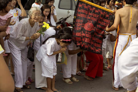 PHUKET, THAILAND OCTOBER 2 2011: A throng of spectators at the annual Phuket Vegetarian Festival bow in respect to a passing Ma Song (spirit medium) during a street procession through the streets of Phuket Town, the provincial capital. のeditorial素材