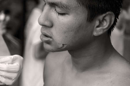 PHUKET, THAILAND OCTOBER 5 2011: A Mah Song (spirit medium) has just had his face piercing extracted at the Sui Boon Tang Chinese Shrine in Phuket Town during the annual Phuket Vegetarian Festival.のeditorial素材