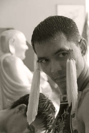 PHUKET, THAILAND OCTOBER 5 2011: A Mah Song (spirit medium) waits to have ceremonial needles removed at the Sui Boon Tang Chinese Shrine in Phuket Town during the annual Phuket Vegetarian Festival.のeditorial素材