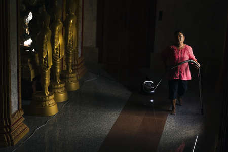 PHUKET, THAILAND APRIL 28 2013: A janitor vacuums the hallway of a building at Chalong Temple in Phuket Town; daily cleaning is the norm due to the large number of visitors.のeditorial素材