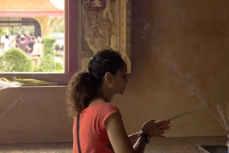 PHUKET, THAILAND APRIL 28 2013: A Thai woman burns and offers incense in an example of Wai Phra at Wat Chalong, the largest Buddhist temple in Phuket.のeditorial素材