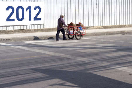 PHUKET, THAILAND FEBRUARY 21 2012: A street peddler makes his way down Rat-tu-thit Road with his pushcart as he hawks snacks and eats in Patong Beach. のeditorial素材