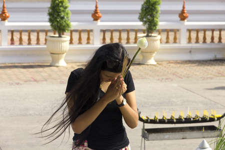 PHUKET, THAILAND MAY 15 2013: A Thai woman holds incense and a flower while offering a prayer at Wat Chalong, the largest Buddhist Temple in Phuket. のeditorial素材