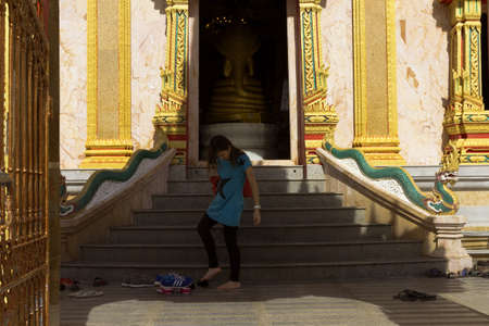 PHUKET, THAILAND MAY 15 2013: A woman visiting Wat Chalong, the largest Buddhist Temple in Phuket, puts her shoes back on after exiting the main stupa. のeditorial素材