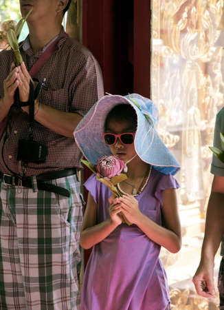PHUKET, THAILAND MAY 15 2013: A Thai girl performs Wai Phra, a Buddhist Offering,  at Wat Chalong in Phuket.のeditorial素材