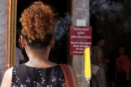 PHUKET, THAILAND MAY 15 2013: A Thai woman lights incense during Wai Phra - a Buddhist Offering - at Wat Chalong, the largest Buddhist Temple in Phuket. のeditorial素材