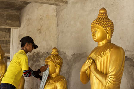 PHUKET, THAILAND FEBRUARY 15 2013: A groundskeeper at the Big Buddha Statue, an iconic symbol of Thai Buddhism in Phuket, cleans a statue of Buddha at the base of the monument.のeditorial素材