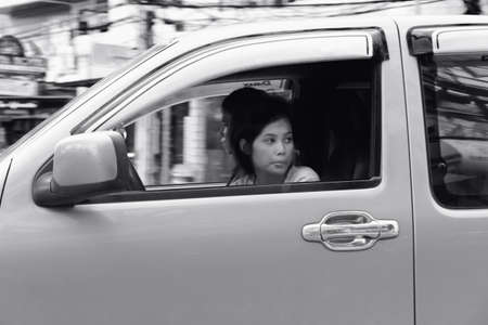 PATONG, PHUKET, THAILAND MAY 7 2012 A young Thai woman rides shotgun in a pick-up truck as it makes a turn onto Rat-tu-thit Road in Patong Beach. のeditorial素材