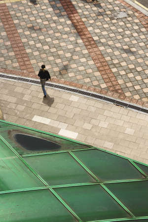 BUKIT BINTANG, KUALA LUMPUR, MALAYSIA OCTOBER 13 2009: A pedestrian walks along tiled sidewalk...