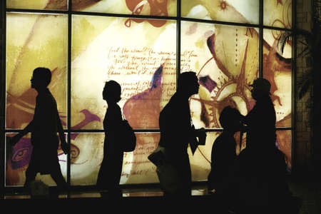 JUNG CEYLONG MALL, PHUKET, THAILAND  JULY 27 2012: A group of shoppers at the Jung Ceylon Shopping Mall in Patong are silhouetted against a lighted backdrop of window panes as they walk past at night. のeditorial素材