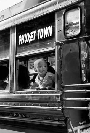 PHUKET, THAILAND SEPTEMBER 6 2011: A Burmese toddler gazes out an open bus window as he waits for departure in Phuket Town. のeditorial素材
