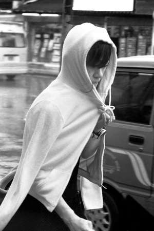 PATONG, PHUKET, THAILAND MAY 6 2012: An Asian tourist on holiday in Phuket covers herself during a sudden rain squall on Rat-tu-thit Road in Patong Beach.のeditorial素材