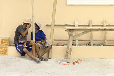 PATONG BEACH, PHUKET, THAILAND AUGUST 11 2011: A father working at a construction site in Patong Beach jokes around with his son during a break. のeditorial素材