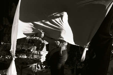 KATHU, PHUKET, THAILAND MAY 13 2013: A vendor at the Kathu Fresh Market in Phuket drapes a screen over her shoulders to ward off the hot afternoon sun.のeditorial素材