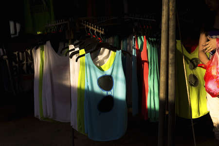 WAT KARON MARKET, KARON, PHUKET, THAILAND FEBRUARY 16 2013: A woman walks by a rack display of T-shirts and singlets for tourists at Temple Karonのeditorial素材