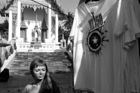 WAT KARON MARKET, KARON, PHUKET, THAILAND FEBRUARY 16 2013: A tourist walks by T-shirts hanging in front of the main stupa on Market Day inside Temple Karon in Phuket.のeditorial素材