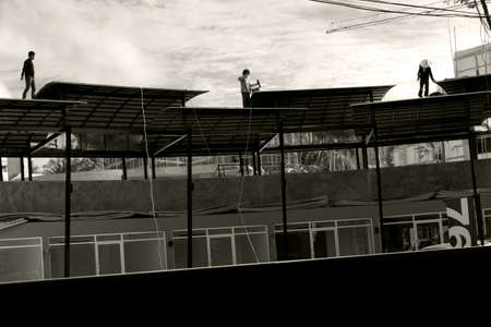 PATONG BEACH, PHUKET, THAILAND AUGUST 2 2012: Three construction workers inspect a newly erected covering over a hotel in Patong Beach.のeditorial素材