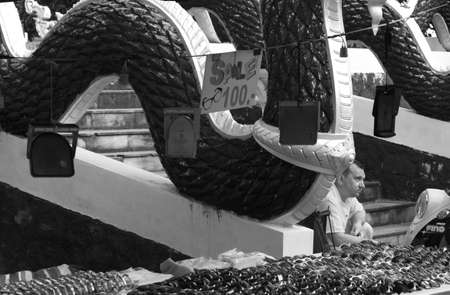 WAT KARON MARKET, KARON, PHUKET, THAILAND FEBRUARY 9 2013: A tourist sits on staircase of a temple building next to market stall Wat Karonのeditorial素材