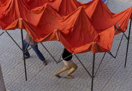 BANZAAN MARKET, PATONG, PHUKET, THAILAND DECEMBER 29, 2012: Two market vendors erect tenting for their stall at the Banzaan Night Market in Patong Beach. のeditorial素材