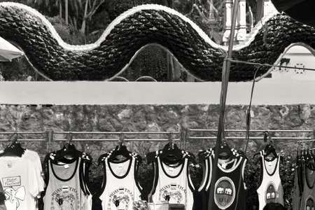 WAT KARON MARKET, KARON, PHUKET, THAILAND FEBRUARY 9 2013: A vendor stall sells T-shirts next to a temple building at Temple Karon's two day a week market.のeditorial素材