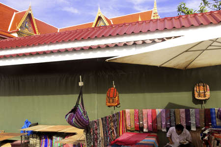 WAT KARON MARKET, KARON, PHUKET, THAILAND FEBRUARY 16 2013: A vendor enjoys a snack at his market stall under a temple building at Wat Karon.のeditorial素材