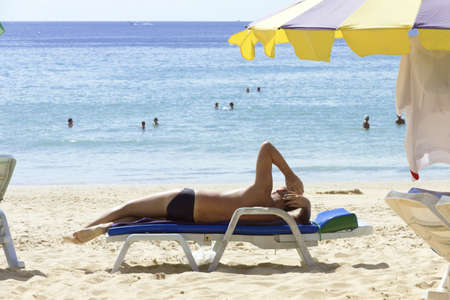 KARON BEACH, PHUKET, THAILAND FEBRUARY 8 2013: A tourist at Karon Beach catches some rays during the...