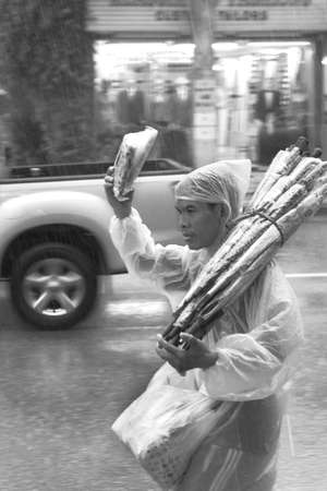 RAT-TU-THIT ROAD, PATONG, PHUKET, THAILAND MAY 6 2012: A street peddler sells rainy day gear during a monsoon rainstorm in Patong Beach.のeditorial素材