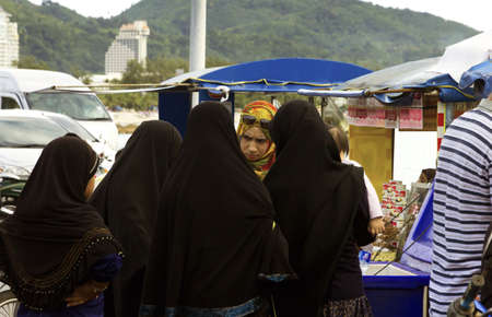 KALIM BEACH, PHUKET, THAILAND APRIL 15 2013: A group of Thai Muslim women chat while buying food at a concession stand along Kalim Beach in Phuket. のeditorial素材