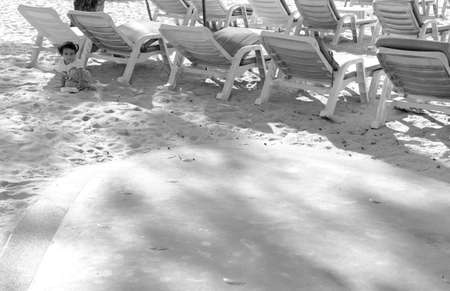 PATONG BEACH, PHUKET, THAILAND JANUARY 22 2-13: A young girl seeks shade under a row of beach lounge chairs.のeditorial素材