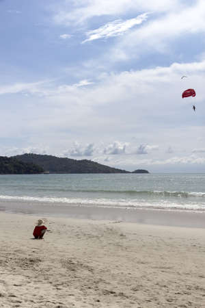 PATONG BEACH, PHUKET, THAILAND AUGUST 18 2011: A parasail vendor in a sombrero watches customer over Patong Beach in southern Thai province of Phuket.のeditorial素材