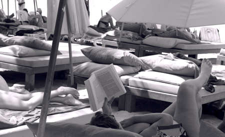 KAMALA BEACH, PHUKET, THAILAND - JANUARY 13 2013: Tourist reads a book under shade of a beach umbrella at Kamala Beach during high season in Phuket.のeditorial素材