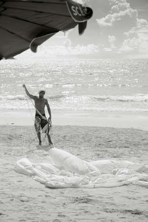 PATONG BEACH, PHUKET, THAILAND AUGUST 23 2011: A jet ski rental operator rolls up a parasail canopy after a ride. のeditorial素材