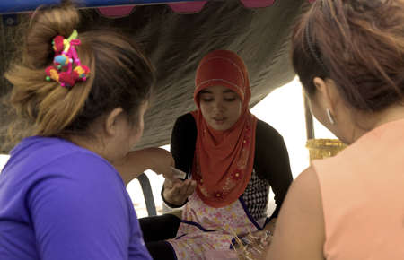 KALIM BEACH, PHUKET, THAILAND APRIL 15 2013: Muslim food vendor makes change for customers at her market stall. のeditorial素材