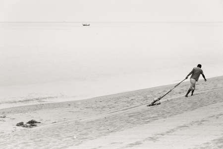 KALIM BEACH, PHUKET, THAILAND FEBRUARY 24 2013: A beach vendor rakes the sand in the early morningのeditorial素材
