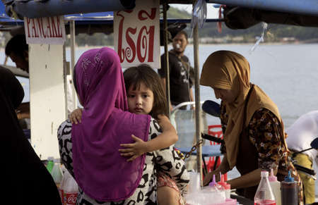 KALIM BEACH, PHUKET, THAILAND JAPRIL 15 2013: Mom and daughter buy some Thai style pancakes at food stall. のeditorial素材