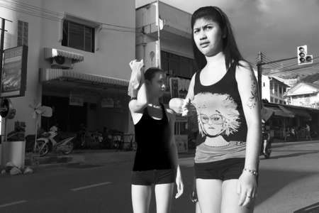 SAINAMYEN ROAD, PATONG, PHUKET, THAILAND JULY 25 2012: Two Thai women walking in Patong try to  shield themselves from the hot sun.のeditorial素材