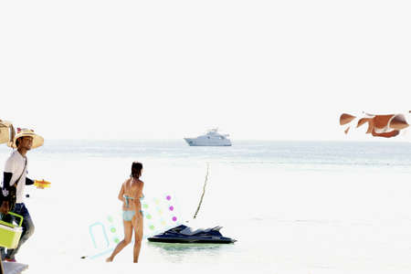 SURIN BEACH, PHUKET, THAILAND JANUARY 31 2013: A tourist holding a beach chair walks past a jet ski and anchored boat off Surin Beach during high season in Phuket.のeditorial素材