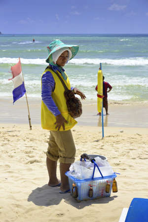 PATONG BEACH, PHUKET, THAILAND AUGUST 11 2011: A beach vendor is fully clothed to protect herself against the hot sun while she works.のeditorial素材