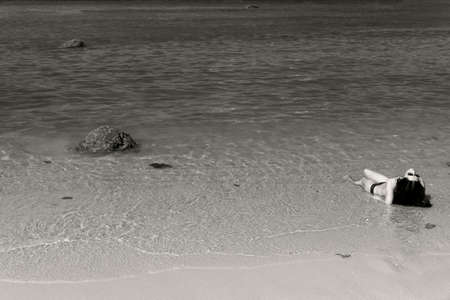 PARADISE BEACH, PHUKET, THAILAND JANUARY 28 2013: A woman on holiday gets a tan in the surf at Paradise Beach during high season in Phuket.のeditorial素材