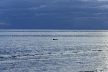 KALIM BEACH, PHUKET, THAILAND APRIL 15 2013: A man in a row boat paddles across the bay  at twilight off Kalim Beach.のeditorial素材