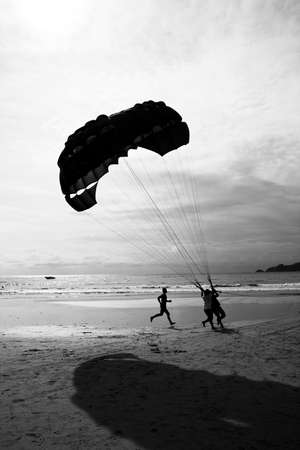 A parasailing tourist lands on Patong Beach in Phuket, Thailand.のeditorial素材