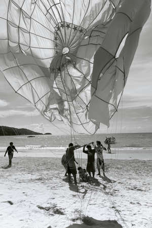 PATONG BEACH, PHUKET, THAILAND, AUGUST 23 2011: Parasail operators untangle a customer from a canopyのeditorial素材