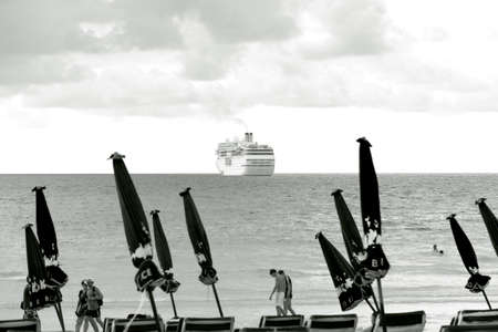PATONG BEACH,  PHUKET, THAILAND NOVEMBER 16 2012: Tourists walk by a cruise ship at anchor and rows of beach umbrellas. のeditorial素材
